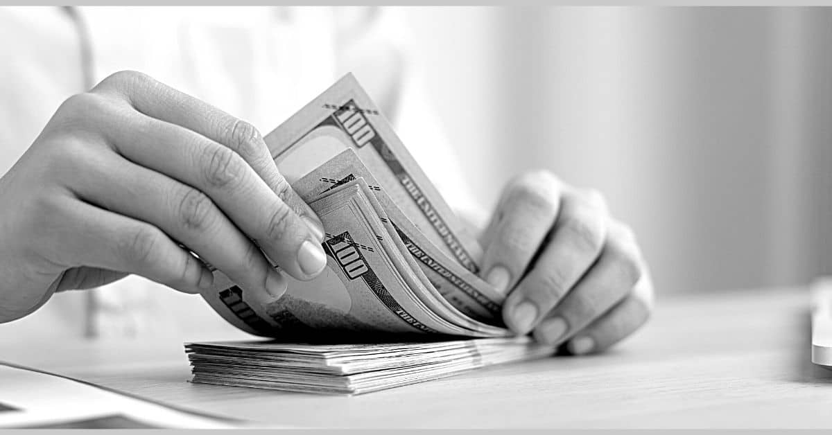 income and wages category page hands holding stack of 100 dollar bills