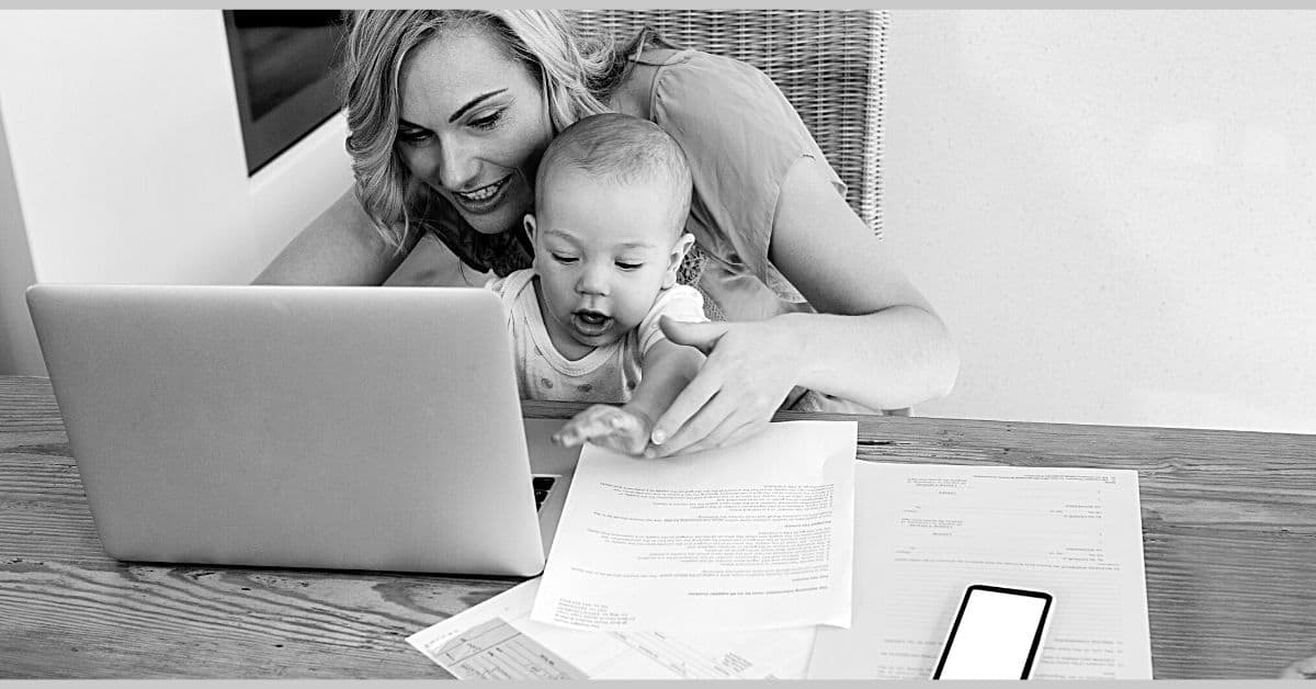 manage money category mom holding baby working on computer