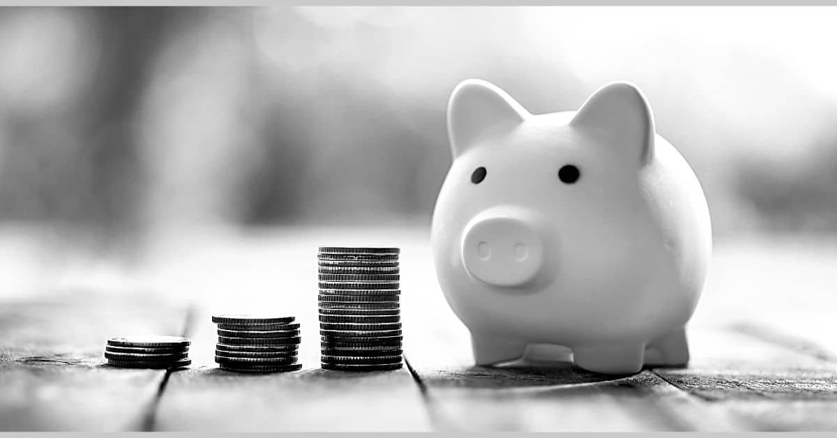 save money category page piggy bank sitting on table with stacks of change by it
